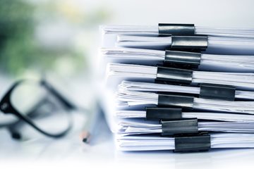 Image of a stack of documents with a pair of glasses and pencil