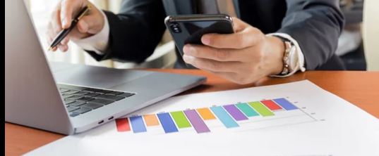Businessman on phone and computer with graphs on the desk